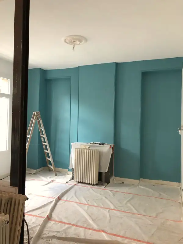 Pièce en cours de travaux, sol protégé et murs peints en bleu canard.